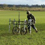 A geophysicist pushing a trolley with ground mapping sensors, creating a geophysical survey of the